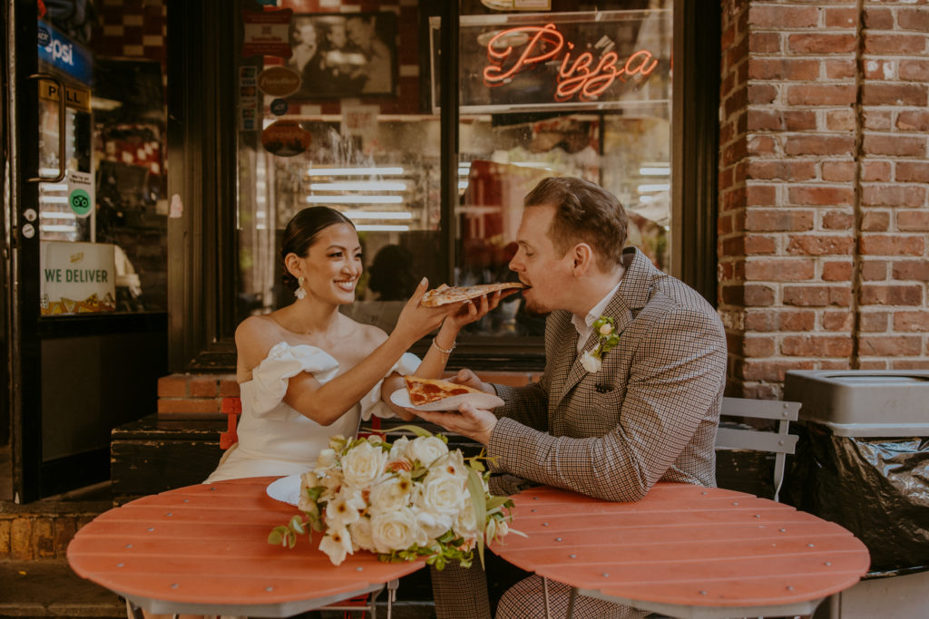 Wedding couple relaxes eats slice of pizza in NYC.